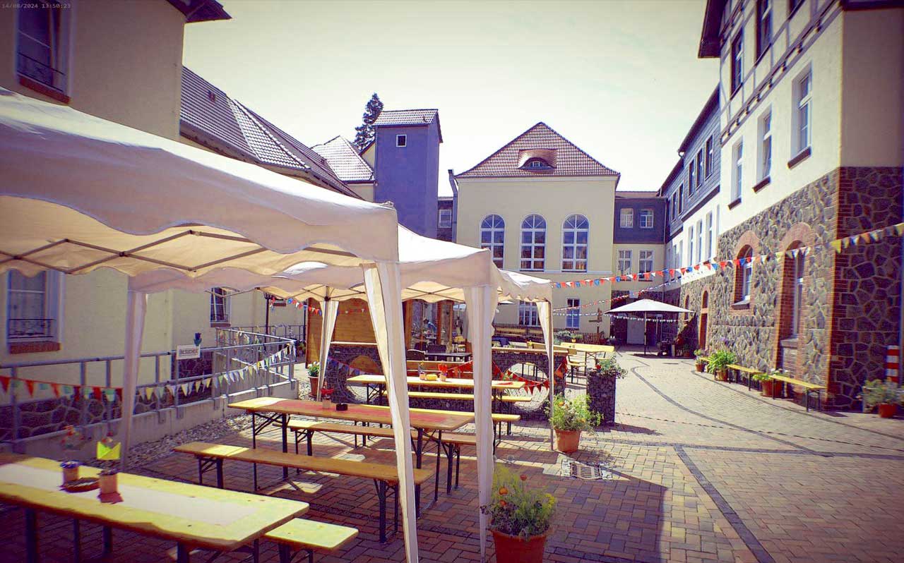 Sommerfest Haus Einetal: Biertische unter Zelten im mit Wimpeln geschmückten Hof des Hauses
