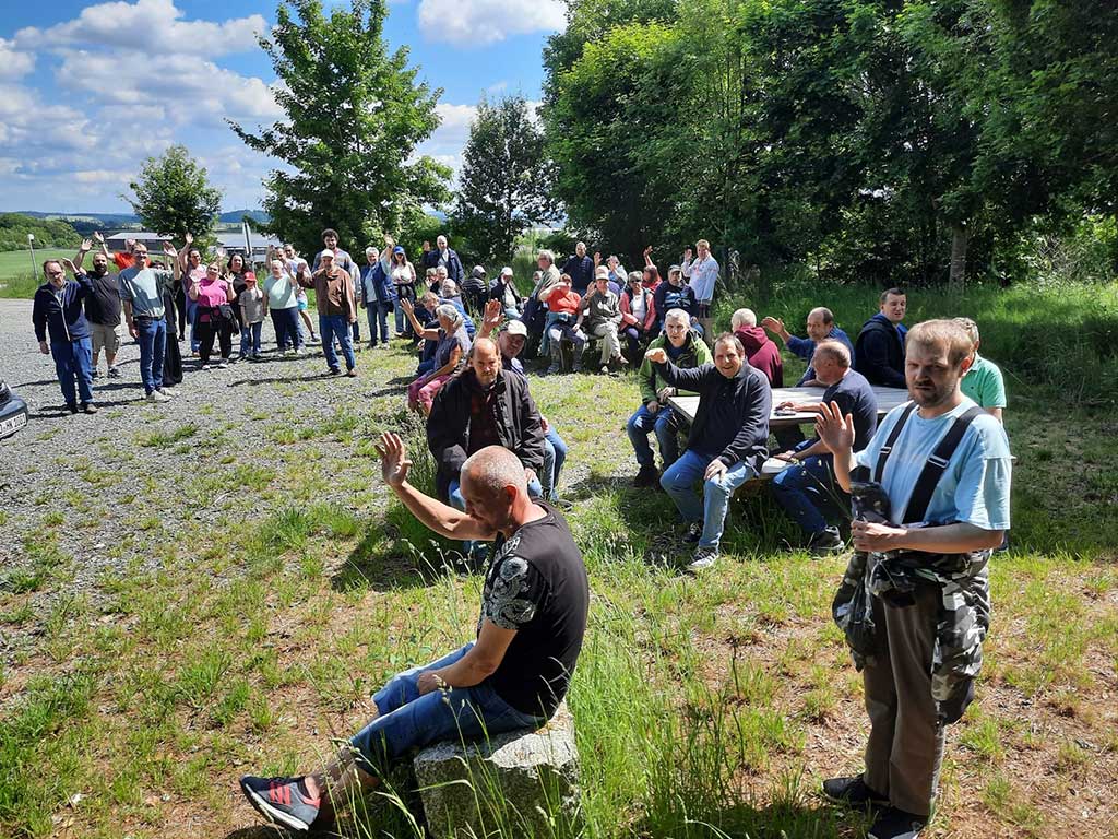 Eine Wandergruppe macht Rast auf einer Waldlichtung im Sonnenschein